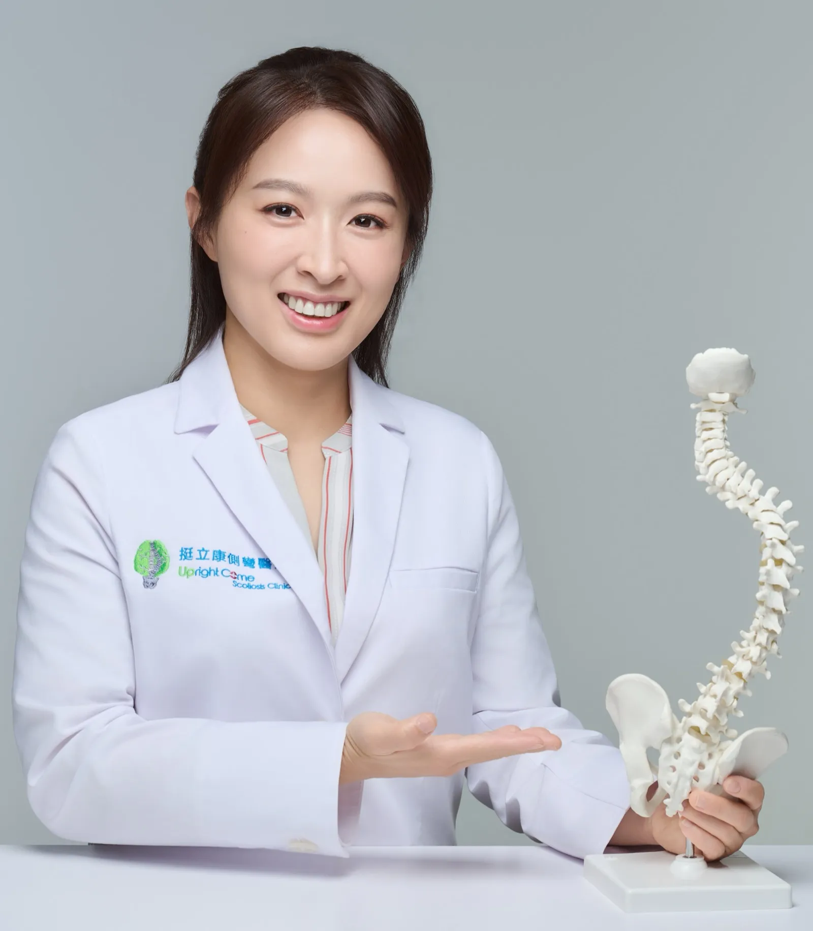 曾琴雁形象照:身穿挺立康側彎醫療白袍,手持脊椎模型微笑